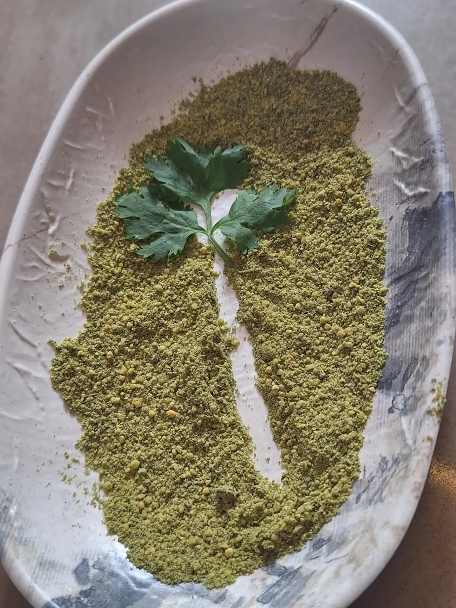 Fresh coriander podi spread on a ceramic plate with a coriander sprig
